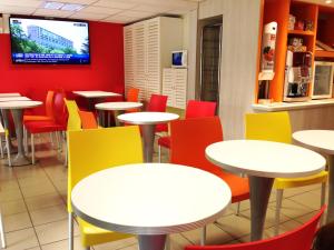 une salle à manger avec des tables et des chaises colorées dans l'établissement Première Classe Epinay Sur Orge Savigny Sur Orge, à Épinay-sur-Orge