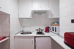a white kitchen with a sink and a microwave at Meliá White House Hotel Apartments in London