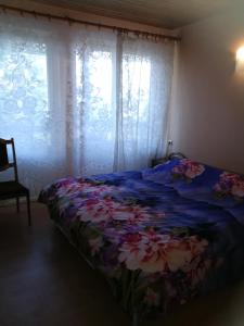 a bed with a blue blanket with flowers on it at Upmaļi in Tērvete