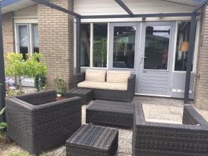 a patio with wicker chairs and a bench and a door at Hygge House Nr. 413 in Andijk