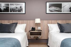 um quarto de hotel com duas camas e uma mesa com um candeeiro em Hotel Capital Bellet em Santiago