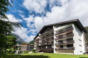 a building in the mountains with a green lawn at Appartement Haus Zalim in Brand