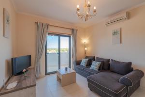 a living room with a couch and a tv at Vista das Ondas - 208 in Albufeira