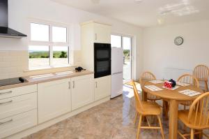 a kitchen with white cabinets and a table and a dining room at Cottage 311 - Clifden in Clifden