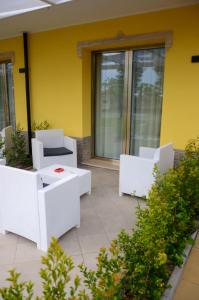 a patio with white chairs and a yellow wall at Hotel Baia Di Trainiti in Briatico
