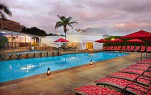 a large swimming pool with red umbrellas and chairs at First Group La Cote D'Azur in Margate