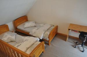 Saint-Amand-en-PuisayeにあるPetite maison aux volets bleusのデスクと椅子が備わる客室内のベッド2台