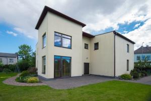 una gran casa blanca con un patio verde en Cozy Apartment Magnolia, en Ventspils