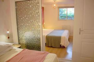 a bedroom with two beds and a sliding glass door at chemin neuf jardin in Gréoux-les-Bains