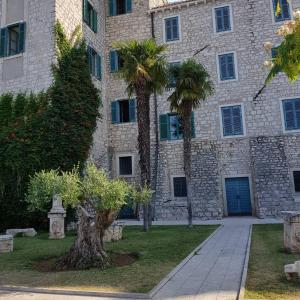a building with two palm trees in front of it at Holiday House ''Villa Flora'' in Šibenik