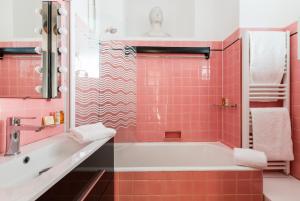 a pink bathroom with a tub and a sink at Veeve - Cosy Gambetta in Paris