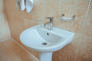 a white sink in a tiled bathroom at JJ Hotel in Vynohradiv