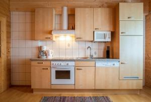 cocina con armarios de madera y nevera blanca en Haus Panoramablick, en Kals am Großglockner