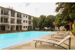 a swimming pool with two benches in front of a building at Riverside Resort in Lap of Nature in Nainital