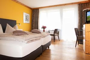 アローザにあるHotel Hohe Promenadeの黄色い壁のベッドルーム1室(ベッド2台付)
