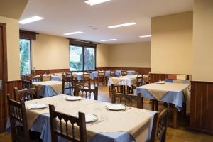 uma sala de jantar com mesas e cadeiras com toalhas de mesa brancas em La Terraza de Picos em Ortiguero