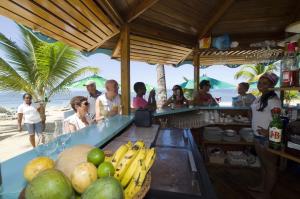 um grupo de pessoas em pé em torno de uma banca de frutas na praia em Hotel Playa Colibri em Las Terrenas