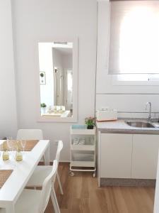 a white kitchen with a white table and chairs at Apartamentos Los Corralejos in Fuengirola
