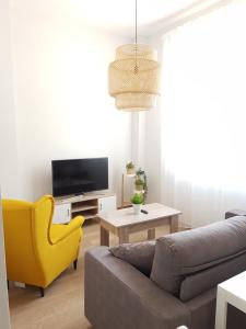 a living room with a couch and a yellow chair at Apartamentos Los Corralejos in Fuengirola