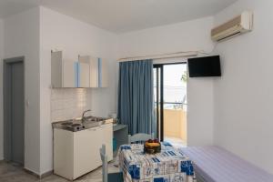 uma pequena cozinha com uma mesa e um lavatório num quarto em Akasti Hotel em Kalamaki
