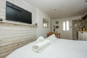 een slaapkamer met een wit bed en een flatscreen-tv bij Brunswick Garden Studio - Patio - by Brighton Holiday Lets in Brighton & Hove