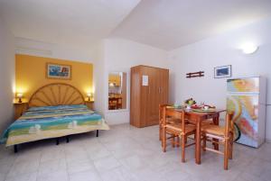 a bedroom with a bed and a table and a desk at Appartamenti Serenity - 2 posti auto - in villa e in centro in Marina di Campo