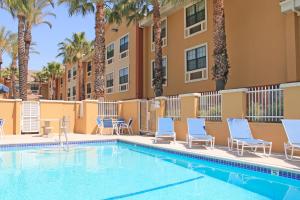 a swimming pool in front of a building with palm trees at Extended Stay America Suites - Los Angeles - Ontario Airport in Guasti