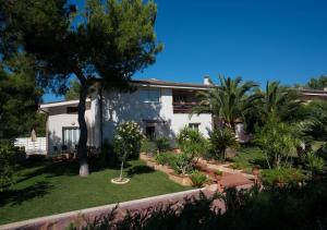 une grande maison blanche avec des arbres et une cour dans l'établissement B&B Nacorè, à Massafra
