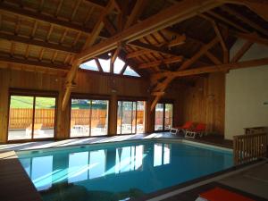 a swimming pool in a house with a large ceiling at Hôtel Soleil des Neiges in Le Sauze