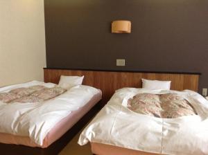 two beds sitting next to each other in a room at Onsen Hotel Itakura in Yamanouchi
