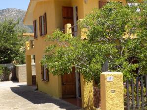Una casa amarilla con un árbol delante. en Casa Vacanze Gardenia, en Solanas