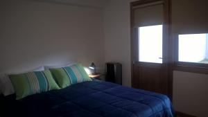 Un dormitorio con una cama azul y una ventana en Las Bandurrias en San Martín de los Andes