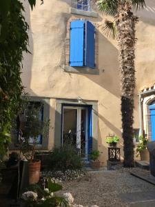 a house with blue doors and a palm tree at Au coeur d'un cocon.... in Pennautier