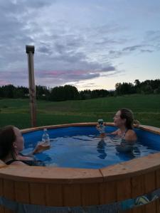 Dos mujeres sentadas en un jacuzzi con bebidas en Willa Mustijoki en Laukkoski