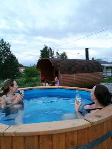 Dos mujeres bebiendo cerveza en un jacuzzi en Willa Mustijoki en Laukkoski