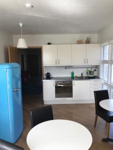 a kitchen with white cabinets and a table and chairs at Framtid Hostel in Djúpivogur