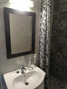 a bathroom with a sink and a mirror and a shower at Central Residence Constanta in Constanţa