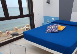 a bedroom with a blue bed with a view of the beach at Sea Windows Suite in Trapani
