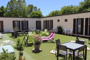 un patio con mesas, sillas, mesas y sillas en Hotel Le Connetable, en Saint-Bonnet-en-Champsaur