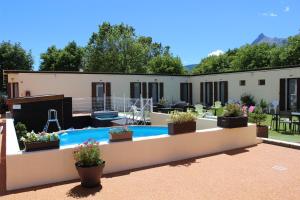 une arrière-cour avec une piscine et des plantes dans l'établissement Hotel Le Connetable, à Saint-Bonnet-en-Champsaur