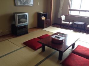 a living room with a couch and a tv at Shiga Kogen Lodge in Yamanouchi