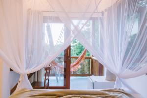 a bedroom with white curtains and a bed and a balcony at Casa Crescente in Trancoso
