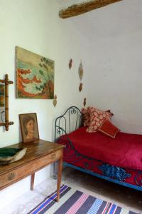 una camera con letto rosso e tavolo in legno di Maison Marthe a Coursegoules