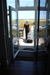a man pulling a suitcase through an open door at Sea Jade Guest House in Bude