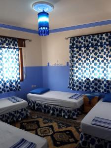 Zimmer mit 3 Betten und blauem Licht in der Unterkunft Dar Al Machichi in Chefchaouen