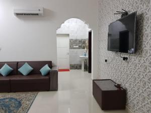 a living room with a couch and a flat screen tv at Alarbee Aljeded in Salalah