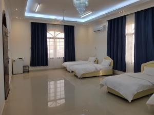 two beds in a room with blue curtains at Alarbee Aljeded in Salalah