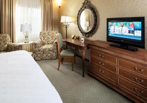 a hotel room with a television and a desk with a bed at Grand Gateway Hotel in Rapid City