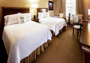 a hotel room with two beds with white sheets at Grand Gateway Hotel in Rapid City +13 photos