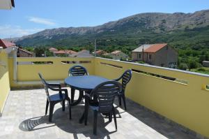 a table and chairs on a balcony with mountains at Apartments Petar in Draga Bašćanska